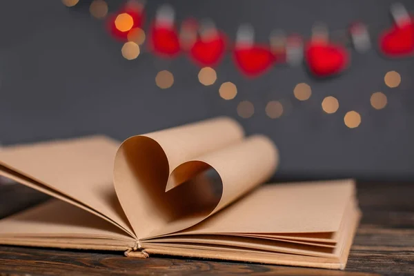 木製のテーブルの上にライト 愛とバレンタインの概念でブックシートから作られた心 — ストック写真