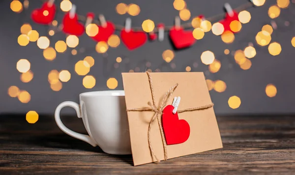 木製のテーブルの上に光 バレンタインの概念を背景にカップの横に心を持つ愛の手紙 — ストック写真