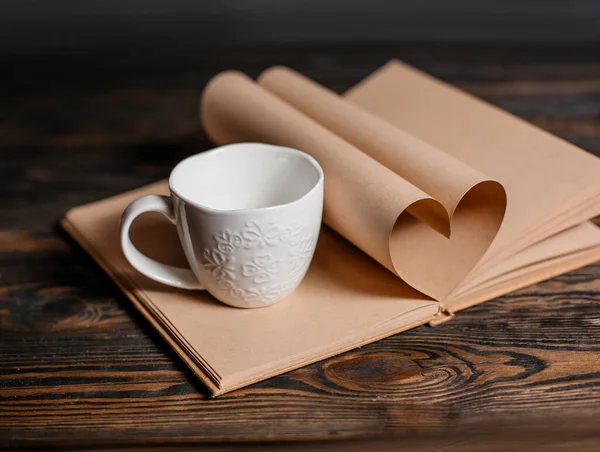 Heart made from book sheets with a cup, love and valentine concept on a wooden table