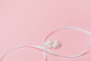 Pembe arka planda geniş kurdeleli bir kalp şekli.