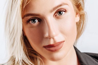 Güzel, mutlu, genç bir kız gri arka planda gülümsüyor.