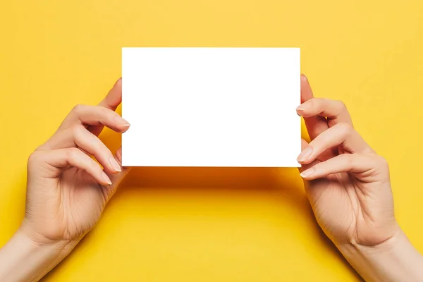 Γυναικεία Χέρια Κρατούν Ένα Λευκό Φύλλο Χαρτιού Κίτρινο Φόντο Διαφημιστικός — Φωτογραφία Αρχείου