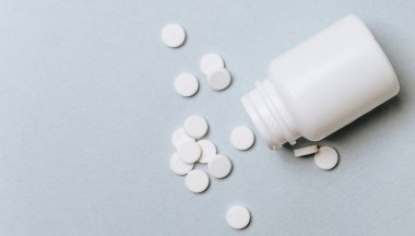 Doktorun masasında beyaz haplar. Tıp konsepti. Tıbbi ürünlerin dozunu belirleme araştırması. Sağlık hizmeti ya da hastalık. Hastanede ya da eczanede ilaç ya da tablet. Açık mavi arkaplan.