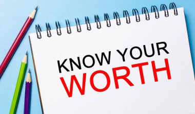 Mavi arka planda kalemler olan beyaz bir not defterine değerini bil. İş konsepti