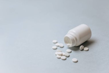 Doktorun masasında beyaz haplar. Tıp konsepti. Tıbbi ürünlerin dozunu belirleme araştırması. Sağlık hizmeti ya da hastalık. Hastanede ya da eczanede ilaç ya da tablet. Açık mavi arkaplan.
