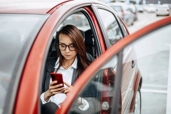 운전대를 소녀는 전화기를 메시지를 읽습니다 주차장에 여자가 자동차 — 스톡 사진