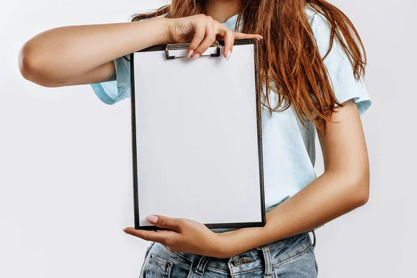 一个年轻漂亮的姑娘拿着一张白纸在一个孤立的灰色背景上 商业概念 一个有着长长的黑头发的女人 刊登广告的地方 — 图库照片