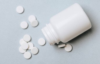 Doktorun masasında beyaz haplar. Tıp konsepti. Tıbbi ürünlerin dozunu belirleme araştırması. Sağlık hizmeti ya da hastalık. Hastanede ya da eczanede ilaç ya da tablet. Açık mavi arkaplan.