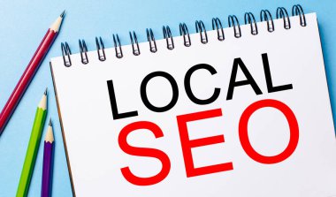 Mavi arka planda kalemler olan beyaz bir not defterinde LOCAL SEO. İş konsepti