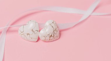 Pembe arka planda geniş kurdeleli bir kalp şekli.