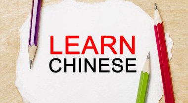 Ahşap arka planda kalemleri olan beyaz bir not defterinden Çince öğren. İş konsepti