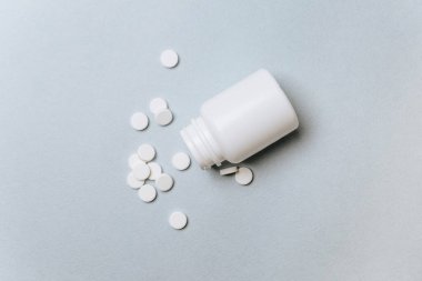 Doktorun masasında beyaz haplar. Tıp konsepti. Tıbbi ürünlerin dozunu belirleme araştırması. Sağlık hizmeti ya da hastalık. Hastanede ya da eczanede ilaç ya da tablet. Açık mavi arkaplan.