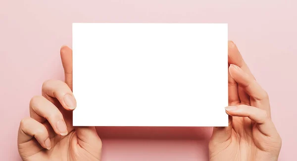 女性的手拿着一张粉红色背景的空白纸片 广告空间 — 图库照片