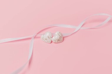 Pembe arka planda geniş kurdeleli bir kalp şekli.