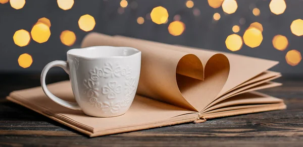 Heart made from book sheets with a cup, love and valentine concept on a wooden table