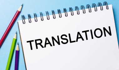 Mavi arka planda kalemler olan beyaz bir not defterine TRANSLATION metni yaz. İş konsepti