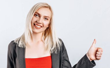 Gülümseyen kadın başparmağını kaldırıyor ve beyaz arka plandan kameraya bakıyor. Pozitif kız şovları gibi. Tamam.