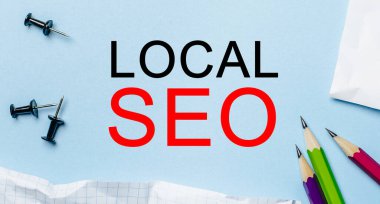 Mavi arka planda kalemler olan beyaz bir not defterinde LOCAL SEO. İş konsepti