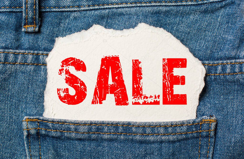 Sale off on white paper in the pocket of blue denim jeans