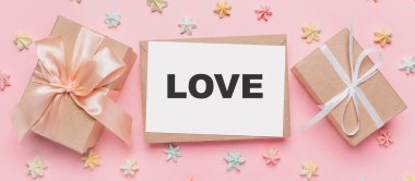 Tatlı, aşk ve sevgililer günü konsepti ile izole edilmiş pembe arka plan üzerine notlu hediyeler