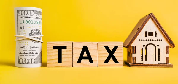 Vergi dairesinin minyatür modeli ve sarı arka planda parası var. Yatırım, gayrimenkul, konut, konut, kazanç, finansal konsept