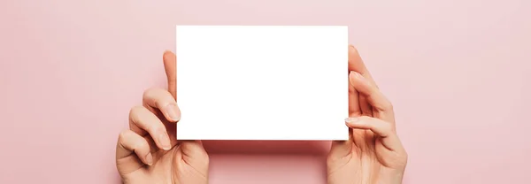 Γυναικεία Χέρια Κρατούν Ένα Λευκό Φύλλο Χαρτιού Ροζ Φόντο Διαφημιστικός — Φωτογραφία Αρχείου