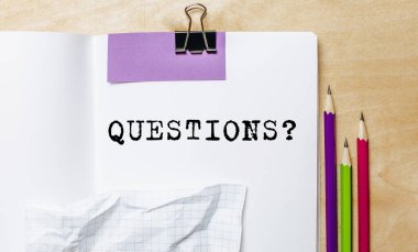 Ofisteki masanın üstünde kalemlerle kağıda yazılmış sorular.