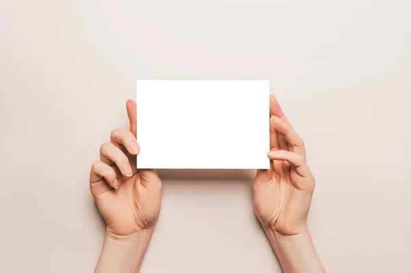 Γυναικεία Χέρια Κρατούν Ένα Λευκό Φύλλο Χαρτιού Μπεζ Φόντο Διαφημιστικός — Φωτογραφία Αρχείου