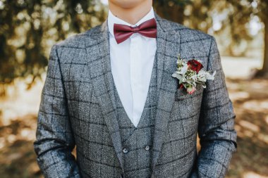 Takım elbiseli damat çiçek yaka çiçekli ve kırmızı papyonlu.