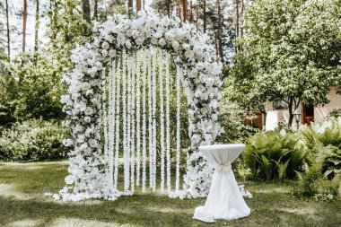 Doğada beyaz çiçeklerle süslenmiş bir düğün töreni.