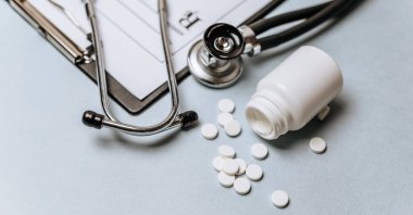 Beyaz haplar, steteskop, doktorun masasında reçete. Tıp konsepti. Tıbbi ürünlerin dozunu belirleme araştırması. Sağlık hizmeti ya da hastalık. Hastanede veya eczanede hap veya hap.