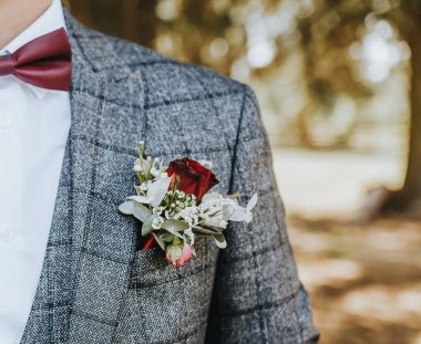 Takım elbiseli damat çiçek yaka çiçekli ve kırmızı papyonlu.