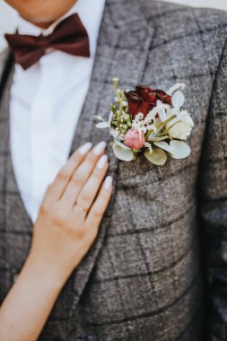 Takım elbiseli damat çiçek yaka çiçekli ve kırmızı papyonlu.