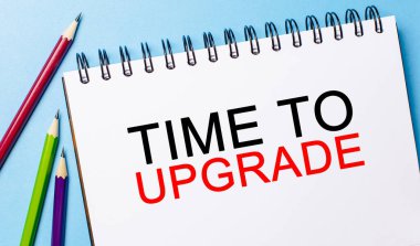 Mavi arka planda kalemler olan beyaz bir not defterini güncelleme zamanı. İş konsepti