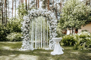 Doğada beyaz çiçeklerle süslenmiş bir düğün töreni.
