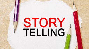 Ahşap arka planda kalemler olan beyaz bir not defterine Hikaye Anlatım 'ı yaz. İş konsepti