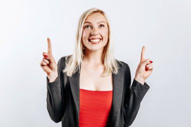 Güzel, genç ve güzel bir kız gülümsüyor. Gri izole arka planda işaret ediyor.