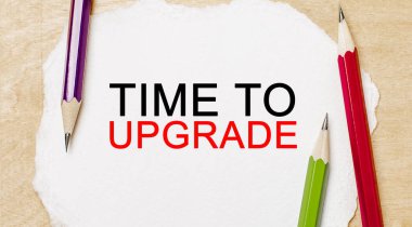 Tahta arka planda kalemler olan beyaz bir not defterini güncelleme zamanı. İş konsepti