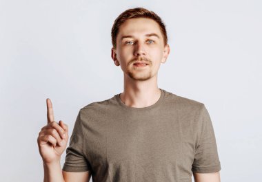 Çekici adam parmağını kaldırır. Yakışıklı adam gelir, uyarır ve gülümser. Genç işadamı, izole edilmiş gri arka plan üzerinden bir seçim yapmayı teklif ediyor..