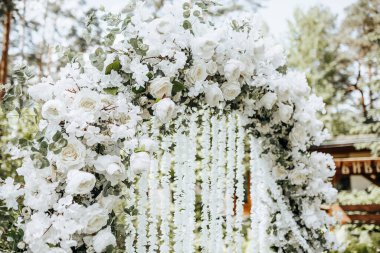 Doğada bir düğün töreni için beyaz çiçeklerle süslenmiş kemer.