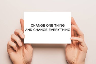 Kadın eli, kart kağıdını mesajla tutar. Bir şeyi değiştir ve sarı arkaplandaki her şeyi değiştir. İş ve finans kavramı