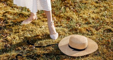 Bahçedeki çimlerin üzerinde hasır şapkalı bir kız. Yazın veya ilkbaharda piknik.