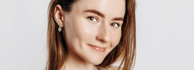 Güzel, genç esmer kadın gülümseyen ve poz veren beyaz izole bir arka planda kameraya bakıyor.