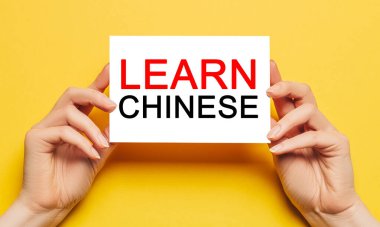 Kadın eli kart kağıdında sarı arka planda Çince öğrenin. Eğitim ve dil kavramı