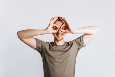 Sakallı genç, yakışıklı esmer adam tamam diyor ve beyaz izole arka planda göz kırpıyor.