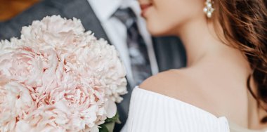 Gelin ve damat düğün gününde sarıl ve bir buket şakayık çiçeğiyle sevgiyi göster