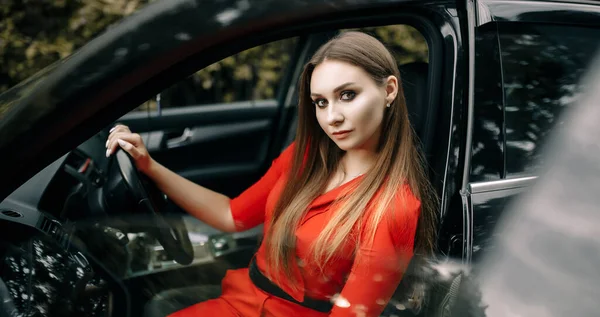 Una Hermosa Joven Con Mono Rojo Sienta Volante Coche Negro — Foto de Stock