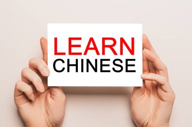 Kadın eli kart kağıdında sarı arka planda Çince öğrenin. Eğitim ve dil kavramı