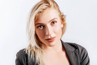 Güzel, mutlu, genç bir kız gri arka planda gülümsüyor.