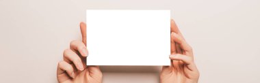 Kadın eli, bej arka planda boş bir kağıt tutuyordu. Reklam alanı